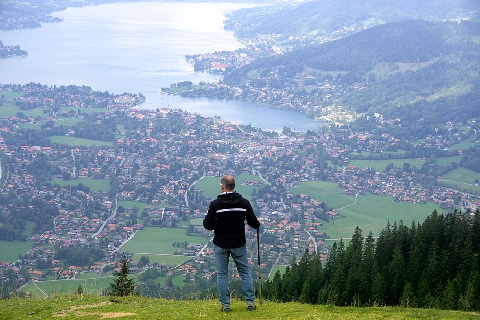 A hiker enjoys a breathtaking view of Rottach-Egern, Germany from a mountain peak.